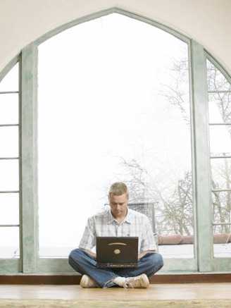 Male Young Adult Sitting on Floor Using Laptop Computer
