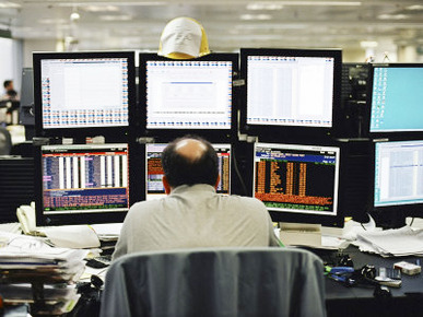 Balding Businessman Working at His Desk in Front of 6 Computer Monitors