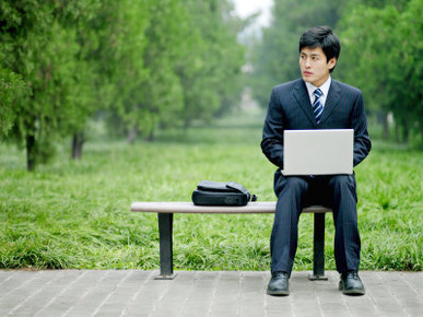 Businessman Seated on a Bench Works on His Laptop Computer